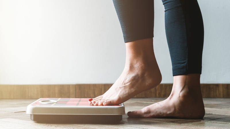 Femme vérifiant ses kilogrammes en montant sur la balance - concept de soin de soi et de positivité corporelle - flambée chaude à gauche